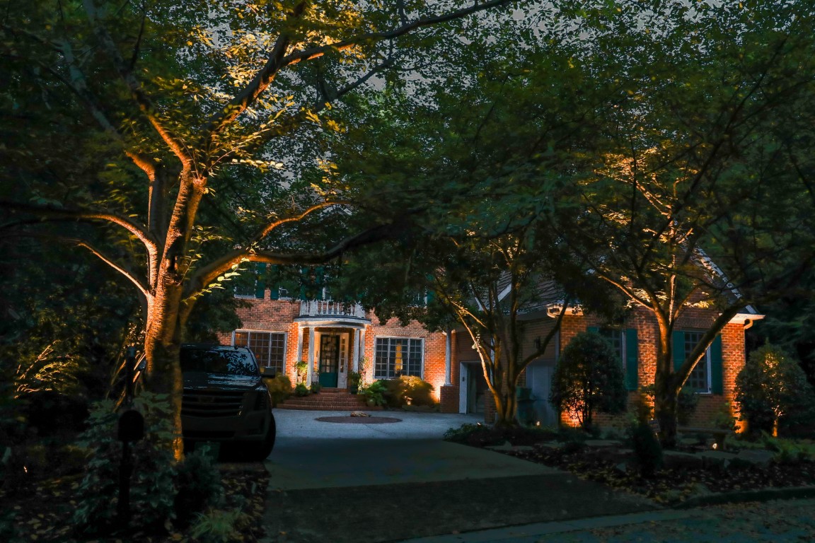 Landscape lighting illuminates the brick house and trees at night in Atlanta.